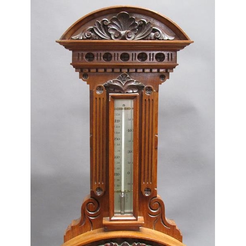 36 - An early 20c aneroid wall barometer, with 20cm diam. silvered dial set into a large heavily carved w... 