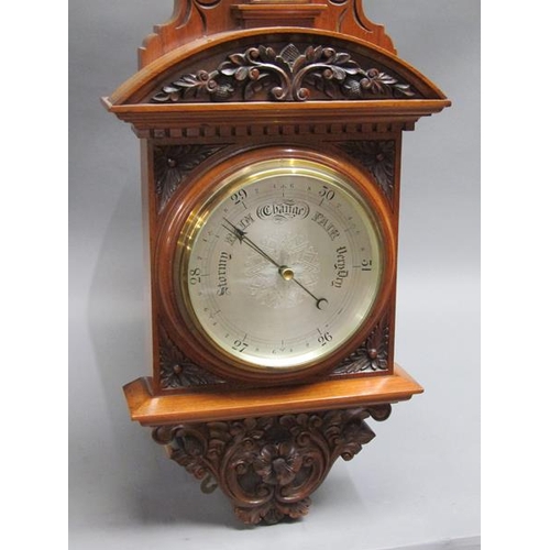 36 - An early 20c aneroid wall barometer, with 20cm diam. silvered dial set into a large heavily carved w... 