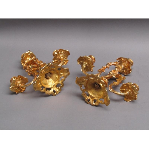 42 - A pair of 19c gilt metal two branch rococo style candelabrum with impressed marks 'EM 23', 24cm w, 2... 