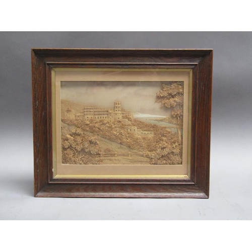 57 - A 19c cork picture of a monastery on a timbered hillside close to a river estuary, framed and glazed... 