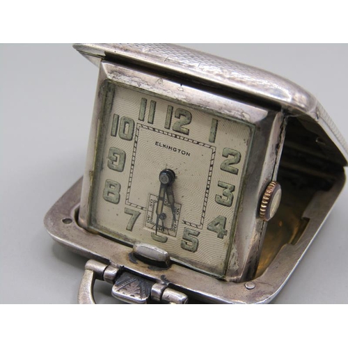 73 - A small Swiss travelling clock in folding silver case made by Sapho and retailed by Elkingtons.  The... 