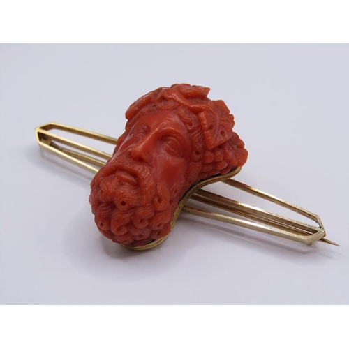 1596 - A 15ct gold bar brooch mounted with a carved coral Bacchus head, 7cm w.