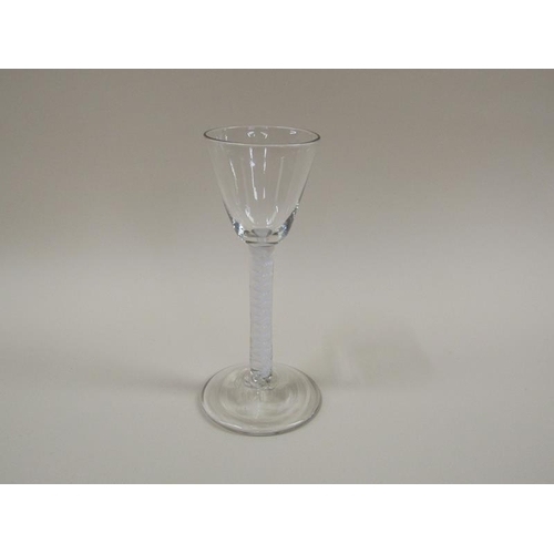 1878 - A mid 18c wine glass with a round funnel bowl on a single series opaque white twist spiral gourd ste... 