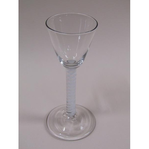 1878 - A mid 18c wine glass with a round funnel bowl on a single series opaque white twist spiral gourd ste... 