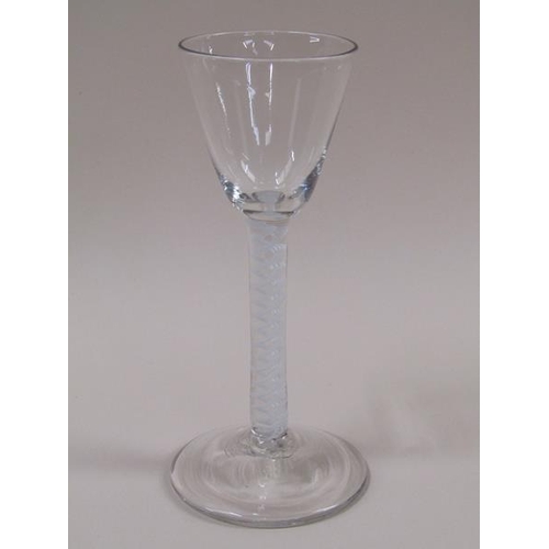 1878 - A mid 18c wine glass with a round funnel bowl on a single series opaque white twist spiral gourd ste... 