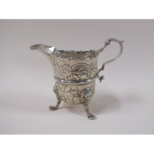 1746 - An 18c silver cream jug, embossed and chased with scroll, leaf and flowers, the base with a milkmaid... 