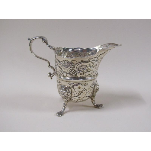 1746 - An 18c silver cream jug, embossed and chased with scroll, leaf and flowers, the base with a milkmaid... 