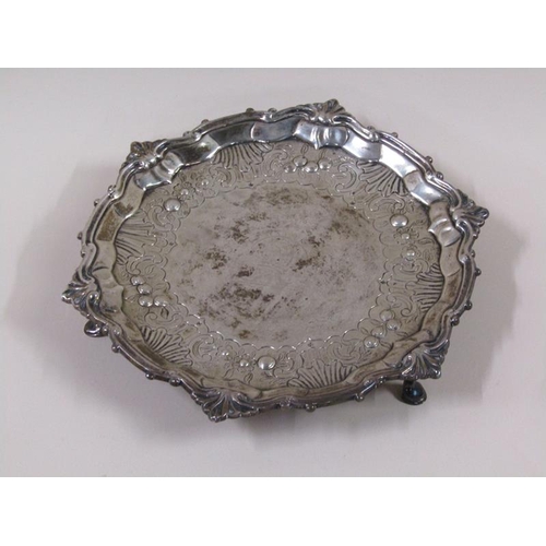 1755 - A late 18c salver of circular form on three legs, having a raised shaped border, assay marks rubbed,... 