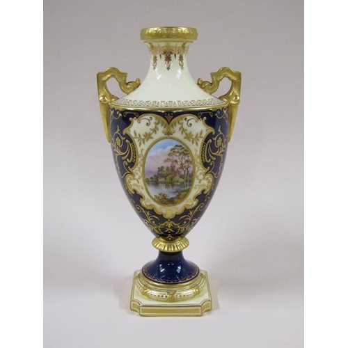 1957 - An early 20c Coalport two handled pedestal vase, hand painted lake scene panels on an ivory and coba... 