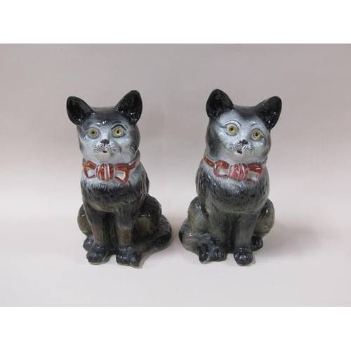 1981 - A pair of 19c Victorian Staffordshire cats, black and white with red bows and glass eyes, 32cm h.