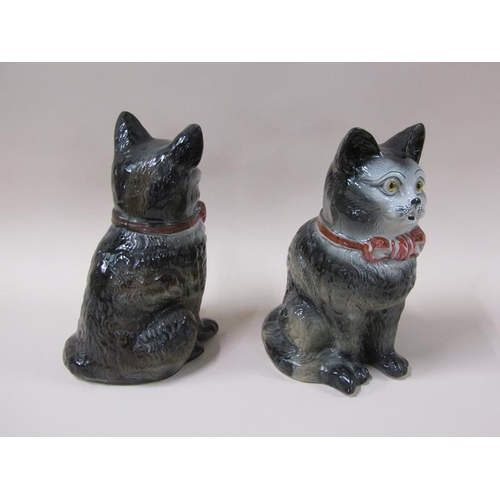 1981 - A pair of 19c Victorian Staffordshire cats, black and white with red bows and glass eyes, 32cm h.