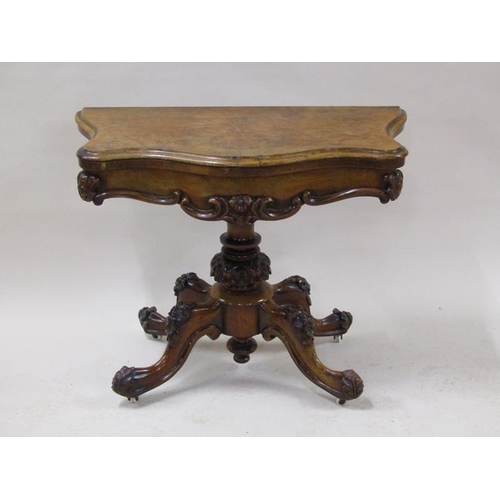 2042 - A mid Victorian burr walnut fold over serpentine card table with a scroll and floral carved frieze, ... 