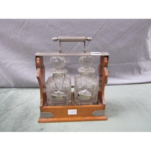 1344 - TWO BOTTLE TANTALUS WITH CUT GLASS BOTTLES AND STOPPERS, BOTH WITH LIQUEUR LABLES, 25cms W