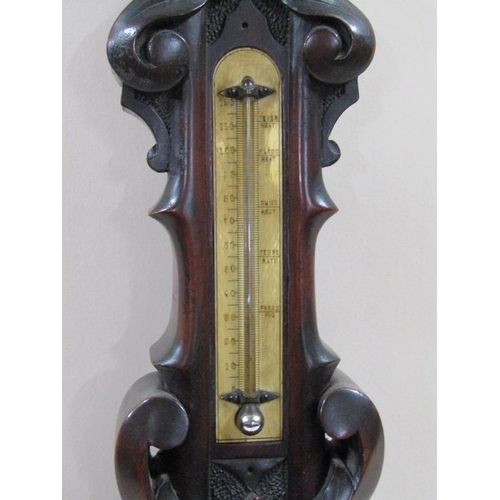 18 - An early 20c aneroid barometer in heavily carved mahogany case of wheel barometer shape.  The 13cm d... 