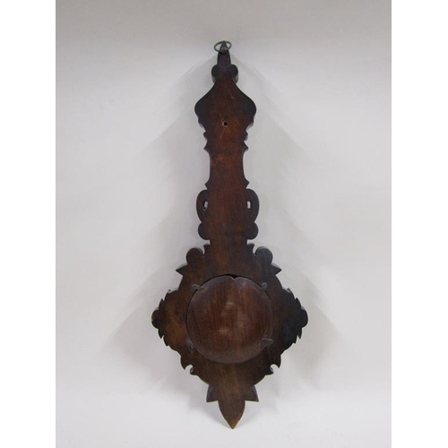 18 - An early 20c aneroid barometer in heavily carved mahogany case of wheel barometer shape.  The 13cm d... 