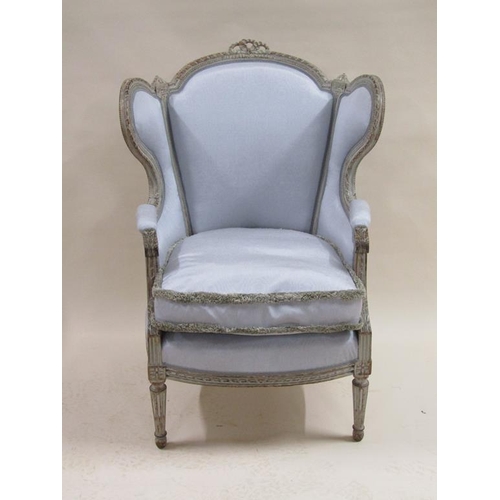 300 - A 19c upholstered wingback armchair with loose squab cushion, having a carved limed show frame.