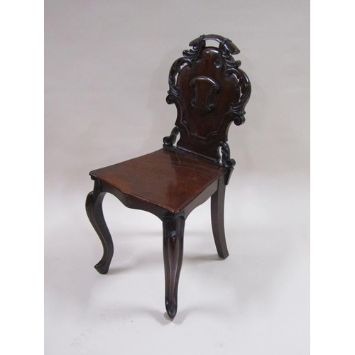 301 - A Victorian mahogany hall chair with a carved shield shaped back panel, solid seat and front slight ... 