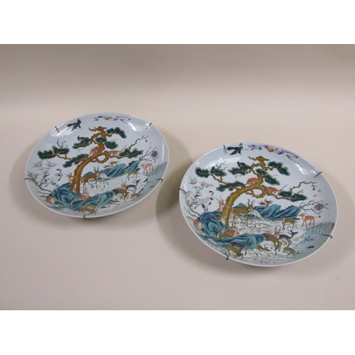 139 - A pair of 19c Chinese famille verte chargers decorated with deer under a pine tree with monkeys and ... 