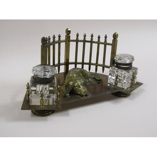 20 - An early 20c gilt metal two bottle inkstand formed as a lying dog backed by a curved fence and havin... 