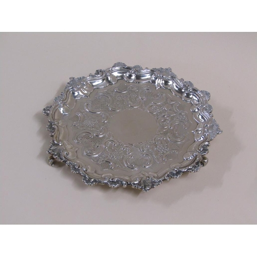 104 - An early 19c silver salver of circular form with a raised border, shell cast with scroll, supported ... 