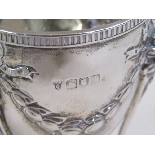 105 - A pair of silver cups on stands, the cups of ovoid form cast with garland and bow, the legs having r... 