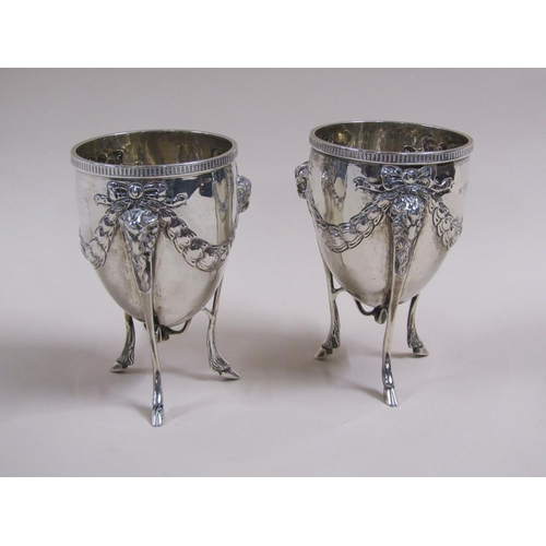 105 - A pair of silver cups on stands, the cups of ovoid form cast with garland and bow, the legs having r... 