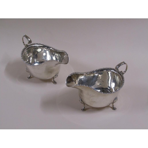 106 - A pair of Georgian style silver gravy boats with open scroll handles, bead and reel cast borders, ea... 