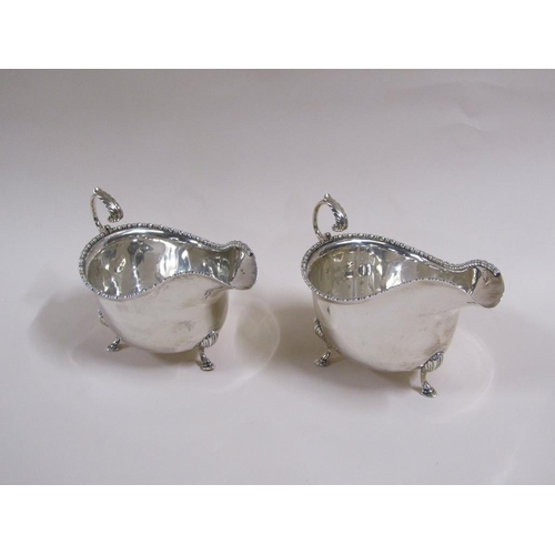 106 - A pair of Georgian style silver gravy boats with open scroll handles, bead and reel cast borders, ea... 