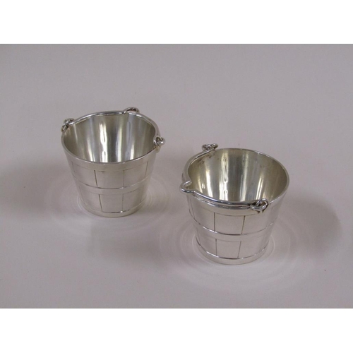 112 - Two early 20c style silver plated milk pails, 7cm h with handles raised.