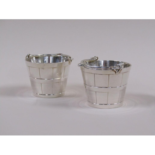 112 - Two early 20c style silver plated milk pails, 7cm h with handles raised.