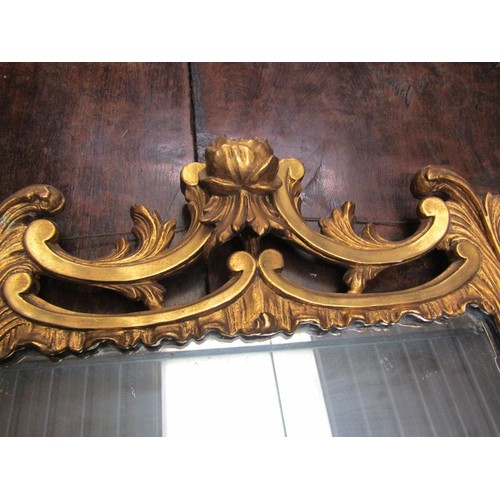 292 - An 18c style gilt wood wall mirror, the frame scroll and leaf carved with rose mounts, 89cm x 53cm.