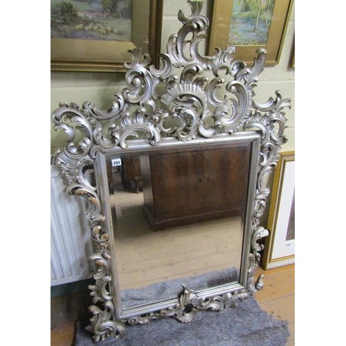 294 - A 19c style Florentine design silvered carved wood scrolling wall mirror,  137cm x 89cm overall.