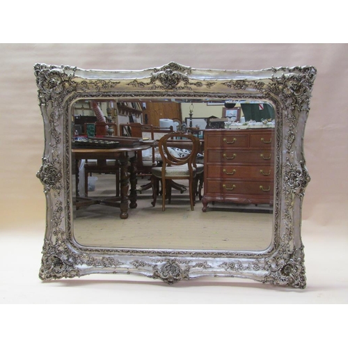 299 - A Georgian style silvered wall mirror of large proportion in a rococo style, embellished with flower... 