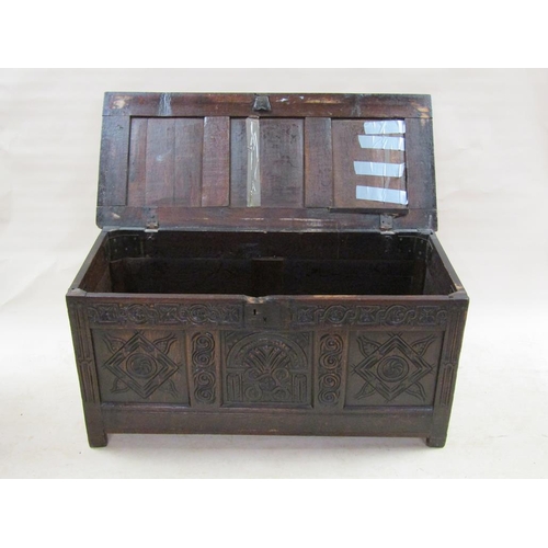 307 - A late 17c oak three panel coffer with a later hinged lid, the coffer panels carved with lunette and... 