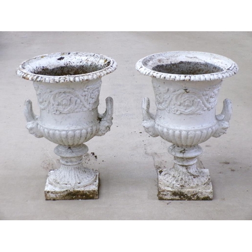 25 - A pair of cast iron campagna shaped urns, two handled, later white painted, on ring cast circular ba... 