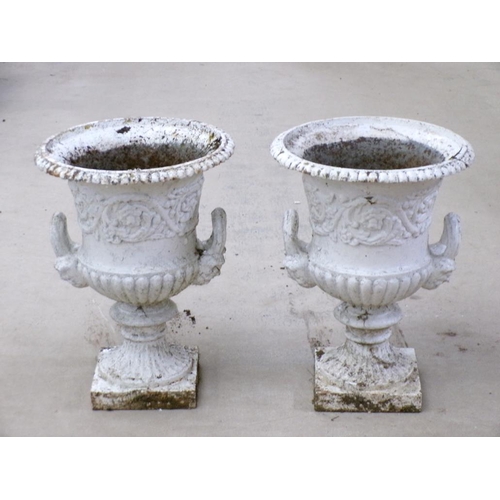 25 - A pair of cast iron campagna shaped urns, two handled, later white painted, on ring cast circular ba... 