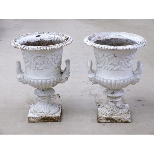 25 - A pair of cast iron campagna shaped urns, two handled, later white painted, on ring cast circular ba... 