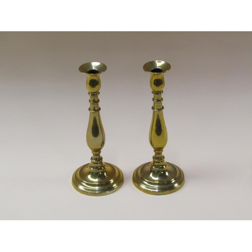 61 - A pair of William IV brass candlesticks with baluster stems and fixed soccles on circular stepped ba... 