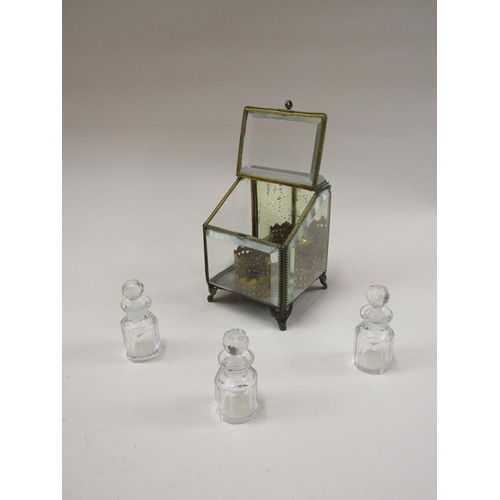 87 - A late Victorian glass scent bottle stand containing three glass bottles, with bevel edge glass wind... 