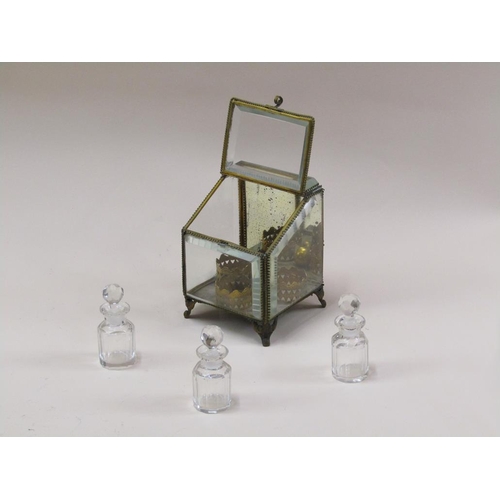 87 - A late Victorian glass scent bottle stand containing three glass bottles, with bevel edge glass wind... 