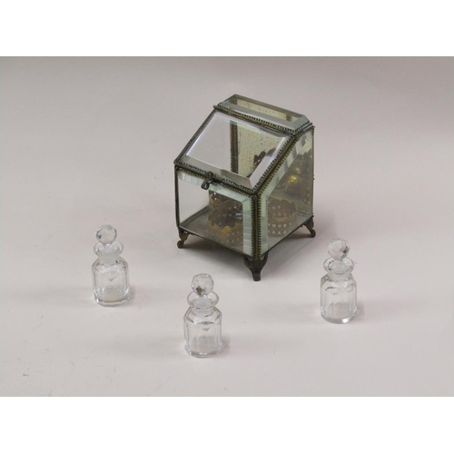 87 - A late Victorian glass scent bottle stand containing three glass bottles, with bevel edge glass wind... 