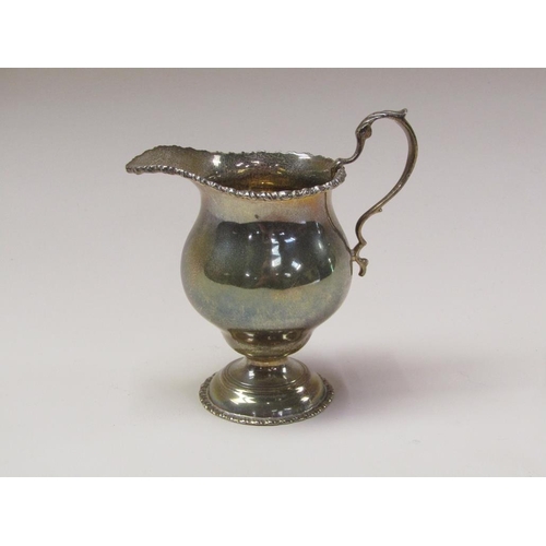 142 - A Victorian silver baluster cream jug with a cast upper rim, scrolling handles and supported on step... 