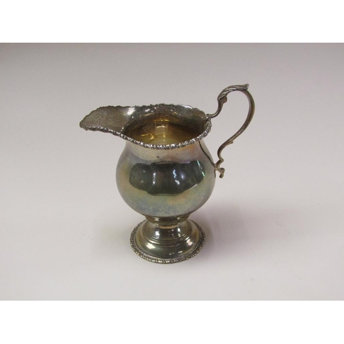 142 - A Victorian silver baluster cream jug with a cast upper rim, scrolling handles and supported on step... 