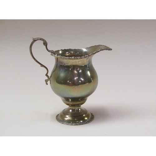 142 - A Victorian silver baluster cream jug with a cast upper rim, scrolling handles and supported on step... 