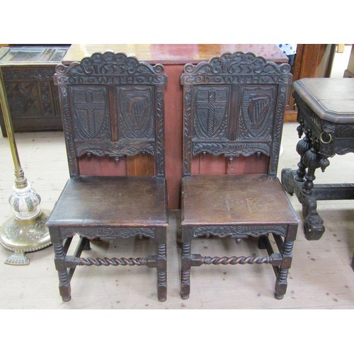 310 - A pair of 17c oak side chairs with solid seats, the back panels carved with two shields, one with a ... 