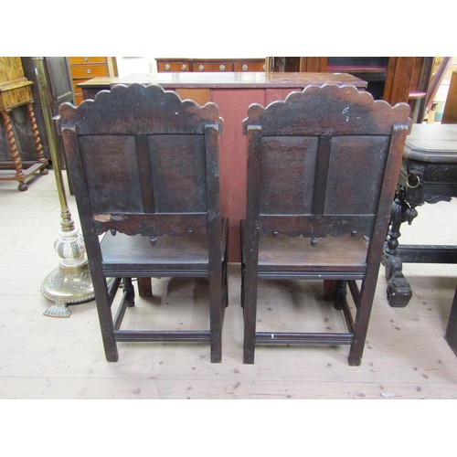 310 - A pair of 17c oak side chairs with solid seats, the back panels carved with two shields, one with a ... 