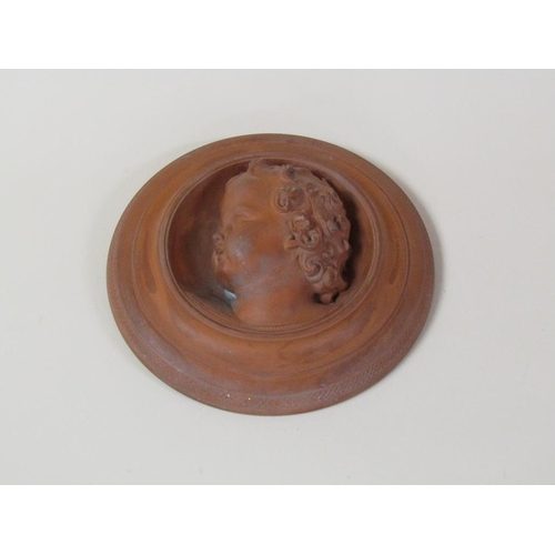 46 - A circular terracotta wall plaque depicting the face of a young child, 27cm diam.