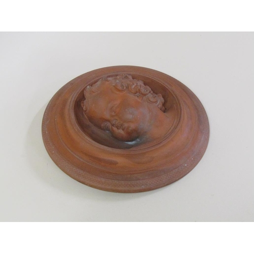 46 - A circular terracotta wall plaque depicting the face of a young child, 27cm diam.