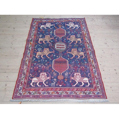 56 - An Iranian woollen rug of red, blue ground decorated with lions and flowers within three borders, 13... 