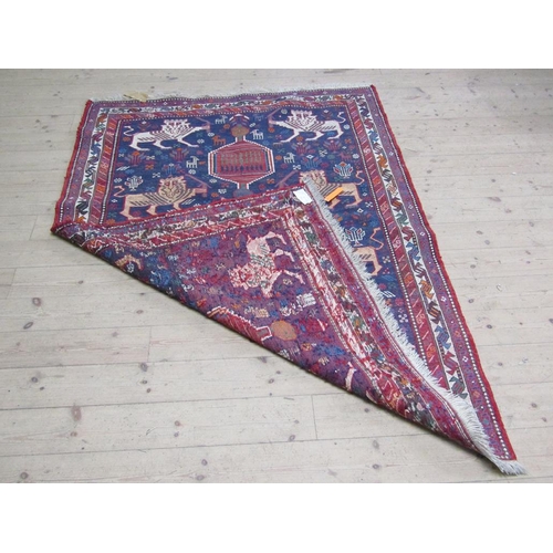 56 - An Iranian woollen rug of red, blue ground decorated with lions and flowers within three borders, 13... 